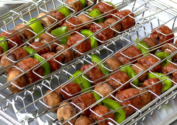 These deliciously grilled Sausage Kabobs served with Pasta are a fun and easy dinner to prepare. They are especially loved by kids. Two kabob grilling baskets filled with sausage kabobs.