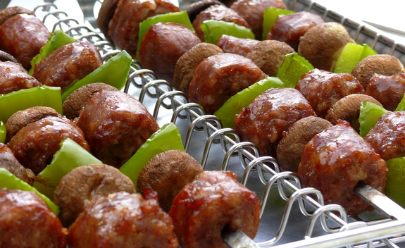 These deliciously grilled Sausage Kabobs served with Pasta are a fun and easy dinner to prepare. They are especially loved by kids. Rows of sausage kabobs sitting in a kabob grilling baket.