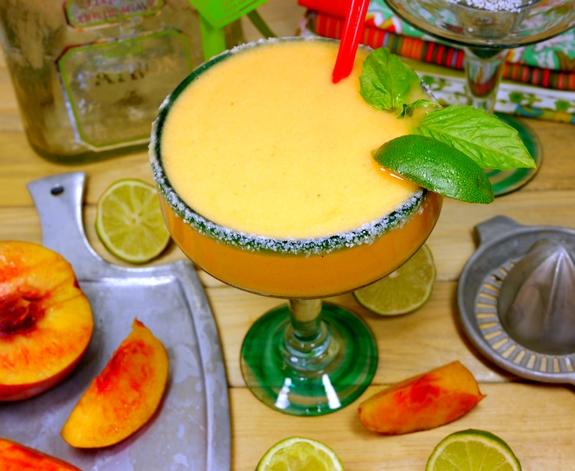 This stone cold, top shelf frozen margarita recipe using frozen nectarines is one for the books. Nectarine-Basil Frozen Margaritas are going to be your new favorite. Overhead of a Nectarine Basil Margaritas with sliced lime and nectarines around it.