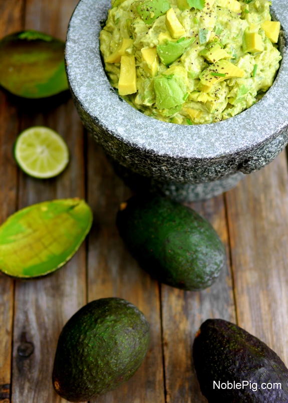 Guacamole in a bowl with avocados.