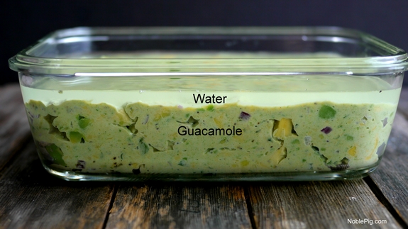 Guacamole in a bowl with water covering it. 