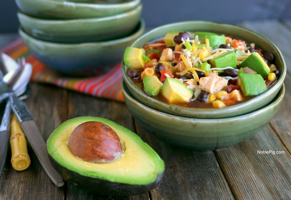 This Mexican Chicken Soup with Avocado will have a delicious and satisfying dinner on the table in 15-minutes. Some nights we need all the help we can get. 15 Minute Mexican Chicken Soup with Avocado in a bowl with a halved avocado.