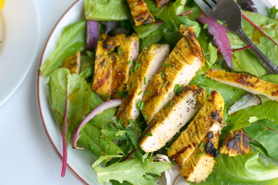 Grilled Turmeric Lemon and Lime Chicken on a bed of lettuce is a great summertime meal