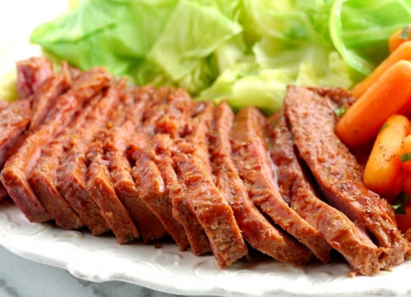 Whiskey-Glazed Corned Beef with cabbage Thinly sliced whiskey-glazed corned beef fanned out on a plate, with glaze glistening under the light