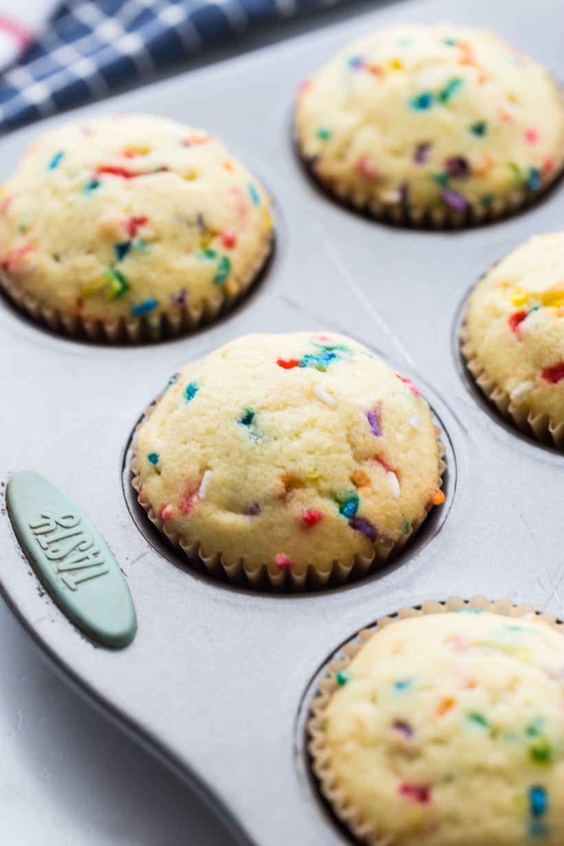 Freshly baked pop rock cupcakes cooling in a muffin tin before topping.