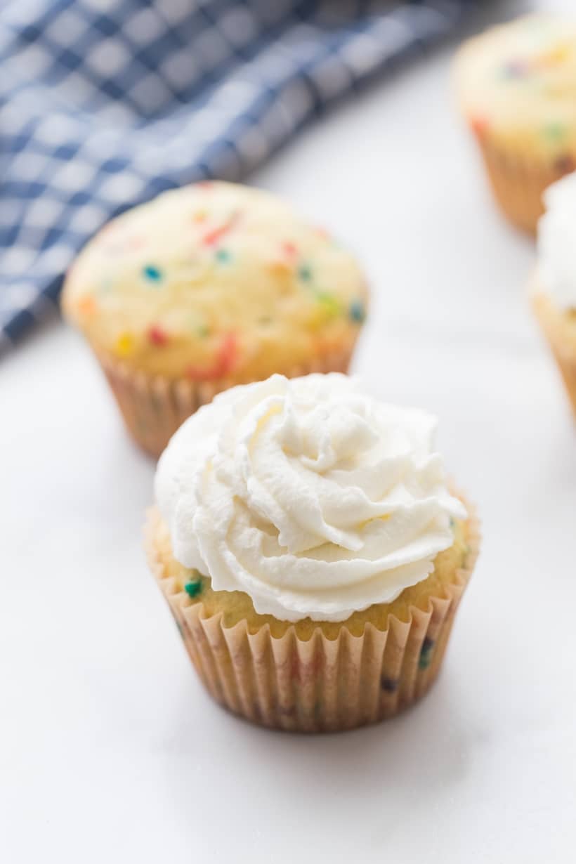 Whipped cream topped patriotic cupcake ready for fresh berries and crackling candy.