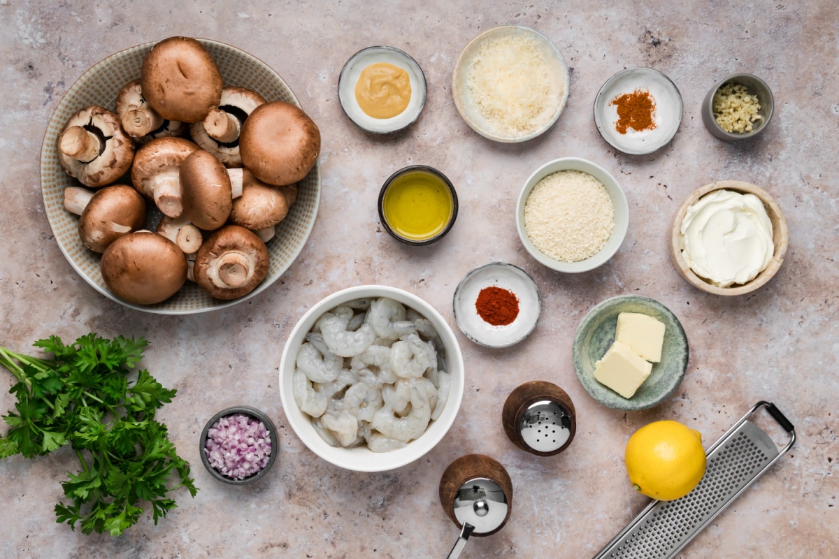 Ingredients for shrimp stuffed mushrooms including cremini mushrooms, raw shrimp, cream cheese, Parmesan, panko and lemon