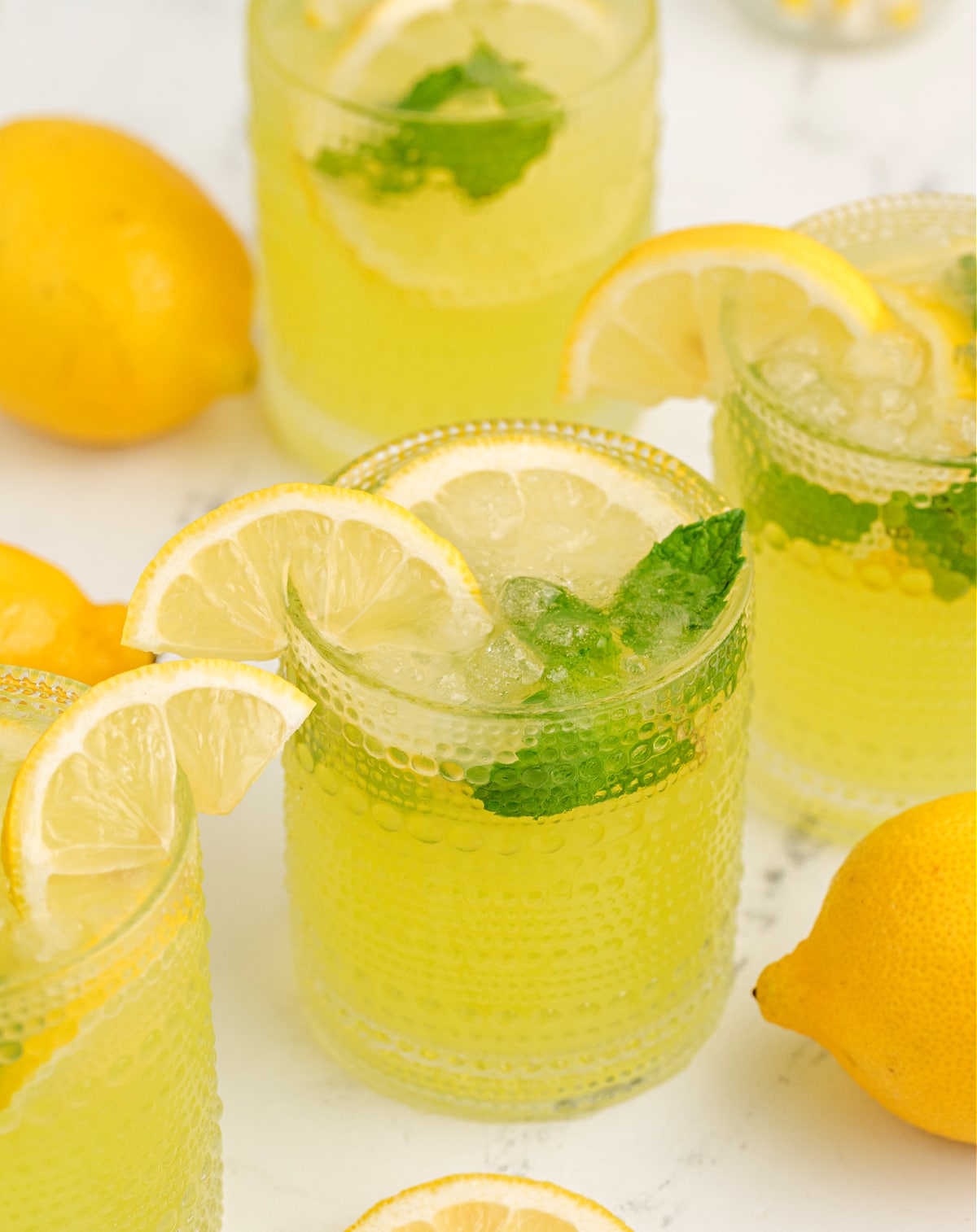 lemonade limoncello cocktail with crushed ice, mint sprig, and a lemon wedge