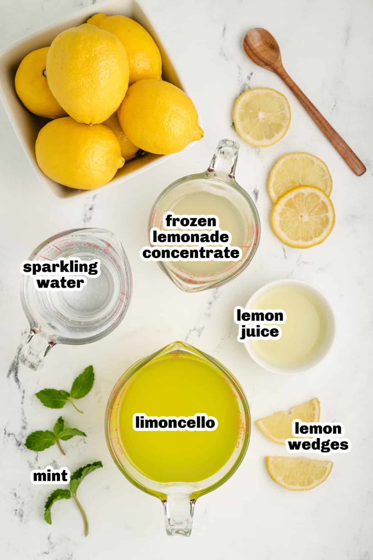 ingredients for a sparkling limoncello cocktail with frozen lemonade concentrate, lemon juice, mint, and sparkling water