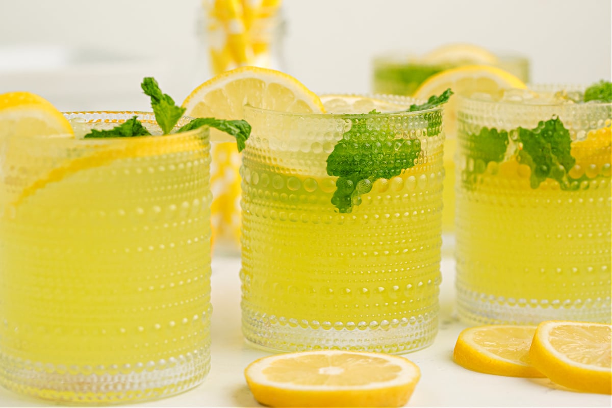 : lemonade limoncello cocktail with crushed ice, mint sprig, and a lemon wedge