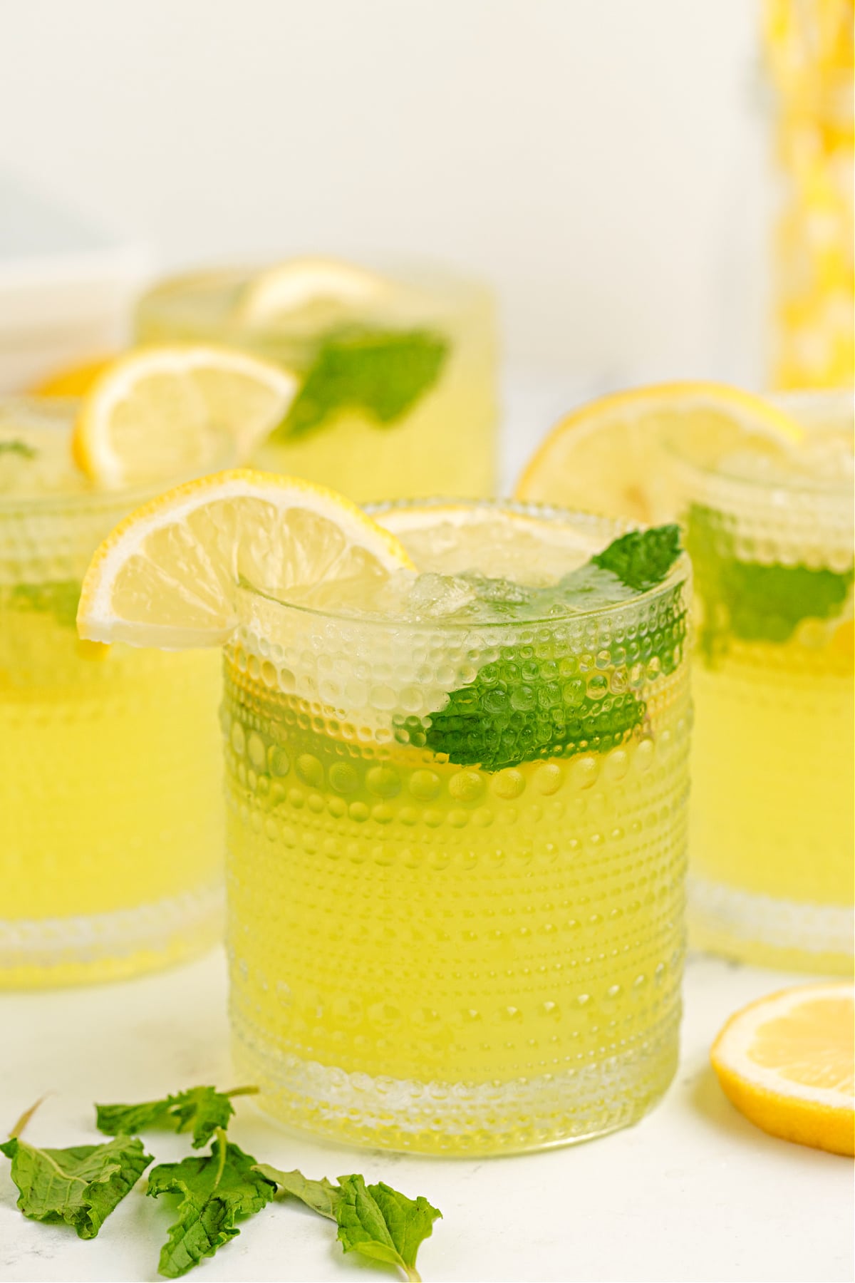 limoncello lemonade with mint and lemon slices over crushed ice in textured glasses