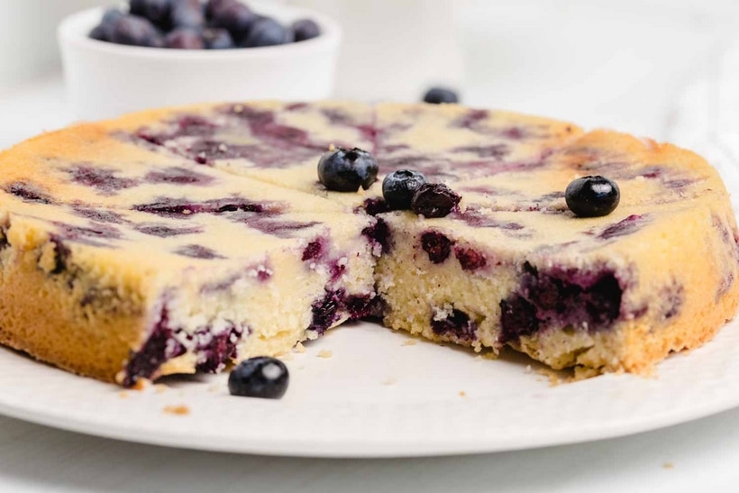 Side view of whole blueberry coffee cake after flipping, showing the golden turbinado sugar crust on the bottom