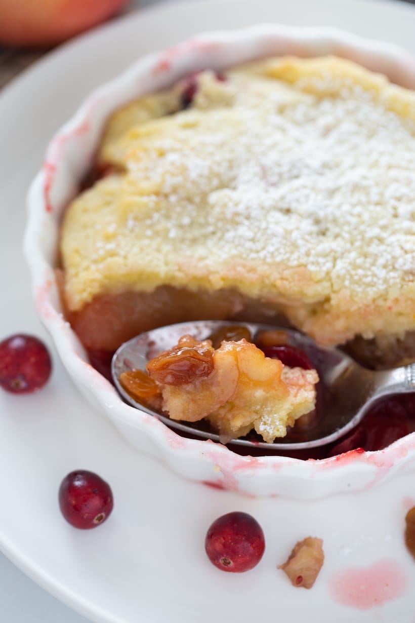 Cranberry apple cobbler with a spoonful taken out, revealing fruit filling.