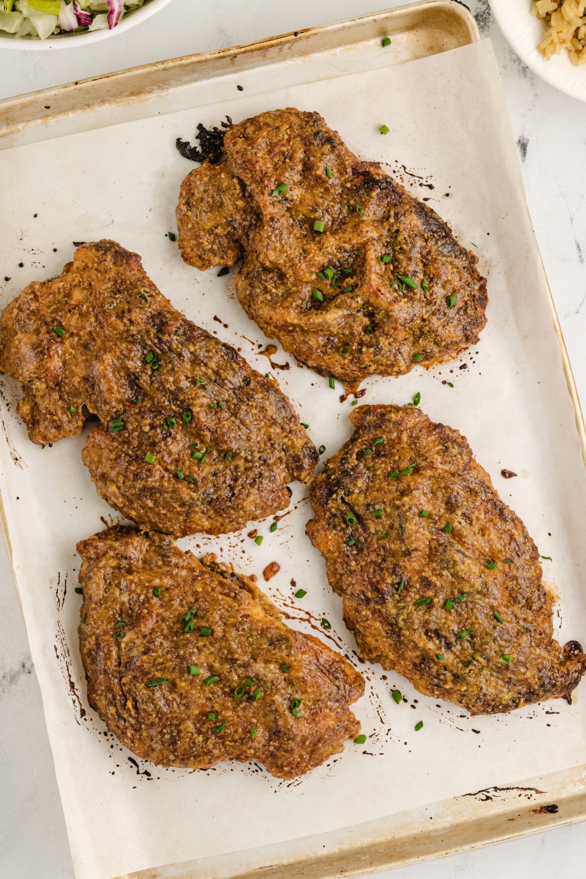 Oven-baked chicken cutlets glazed with maple and mustard on parchment-lined tray