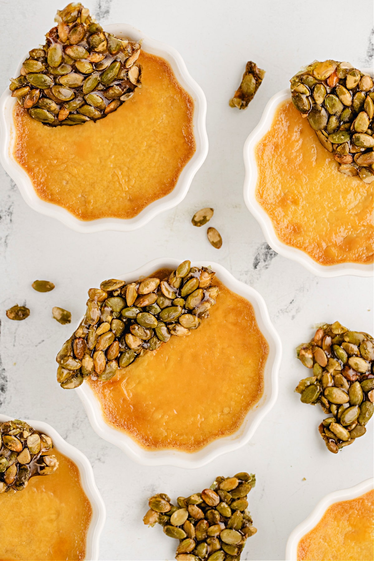 pumpkin chai desserts with pepita brittle Pumpkin chai custards set in scalloped ramekins with shards of pumpkin seed brittle for texture and fall spice contrast.