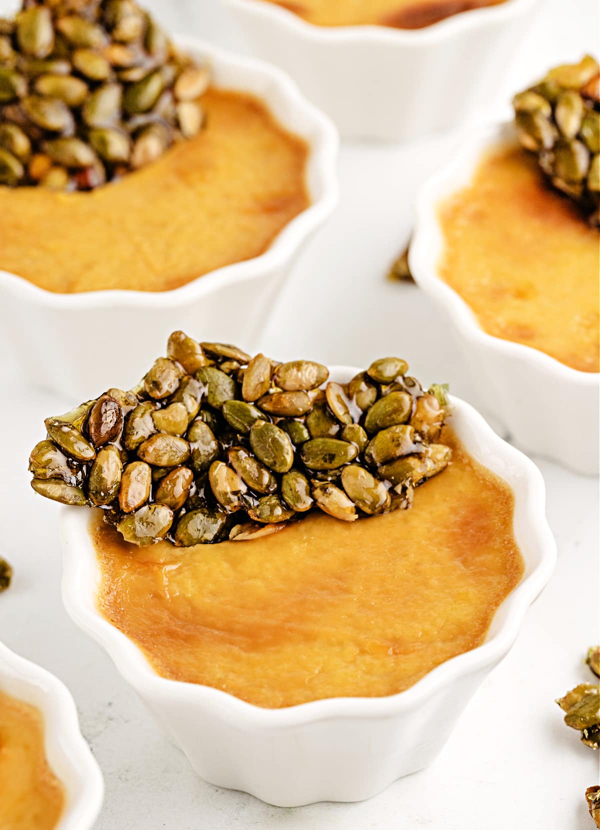 pumpkin chai pots de creme with pumpkin seed brittle Pumpkin Chai Pots de Crème by Noble Pig topped with glossy pumpkin seed brittle, showing the silky baked custard texture up close.