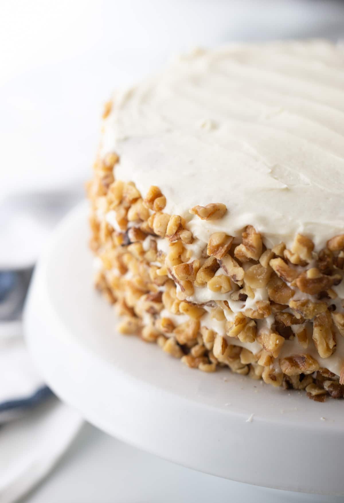 Side view of the whole carrot apple cake with walnuts pressed into the frosting on the sides.