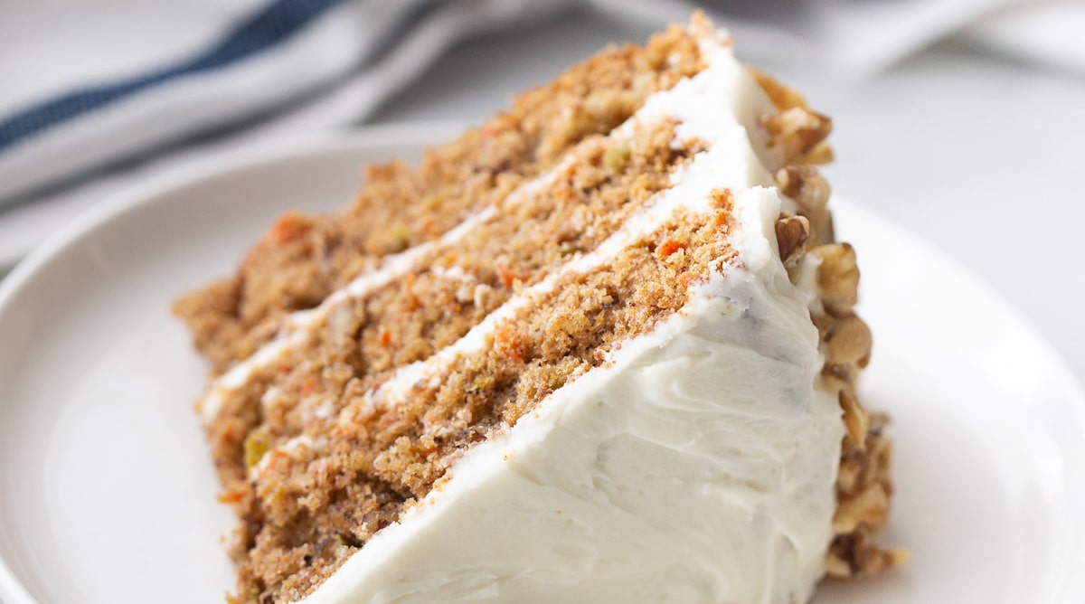Side view of a slice of carrot apple cake showing the layered interior with frosting in between.