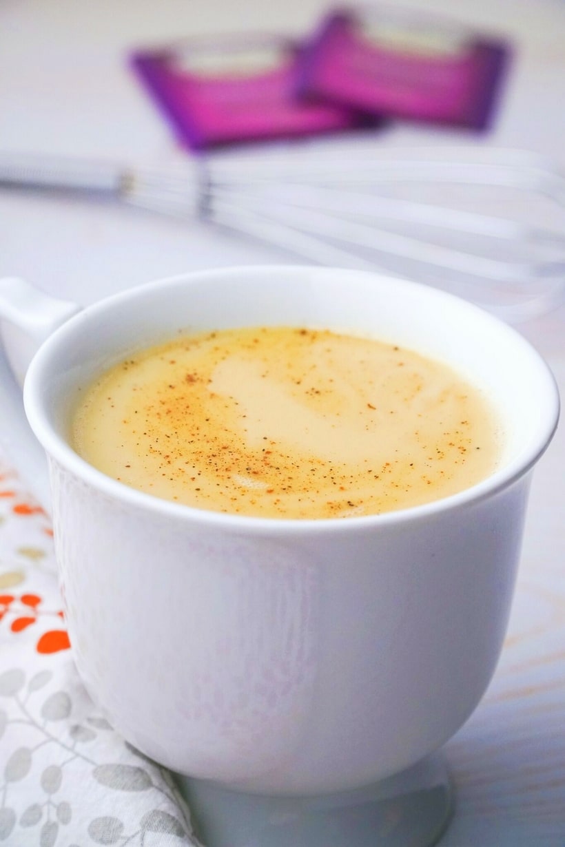 Chai Eggnog in a mug with Darjeeling tea bags and spices in the background.
