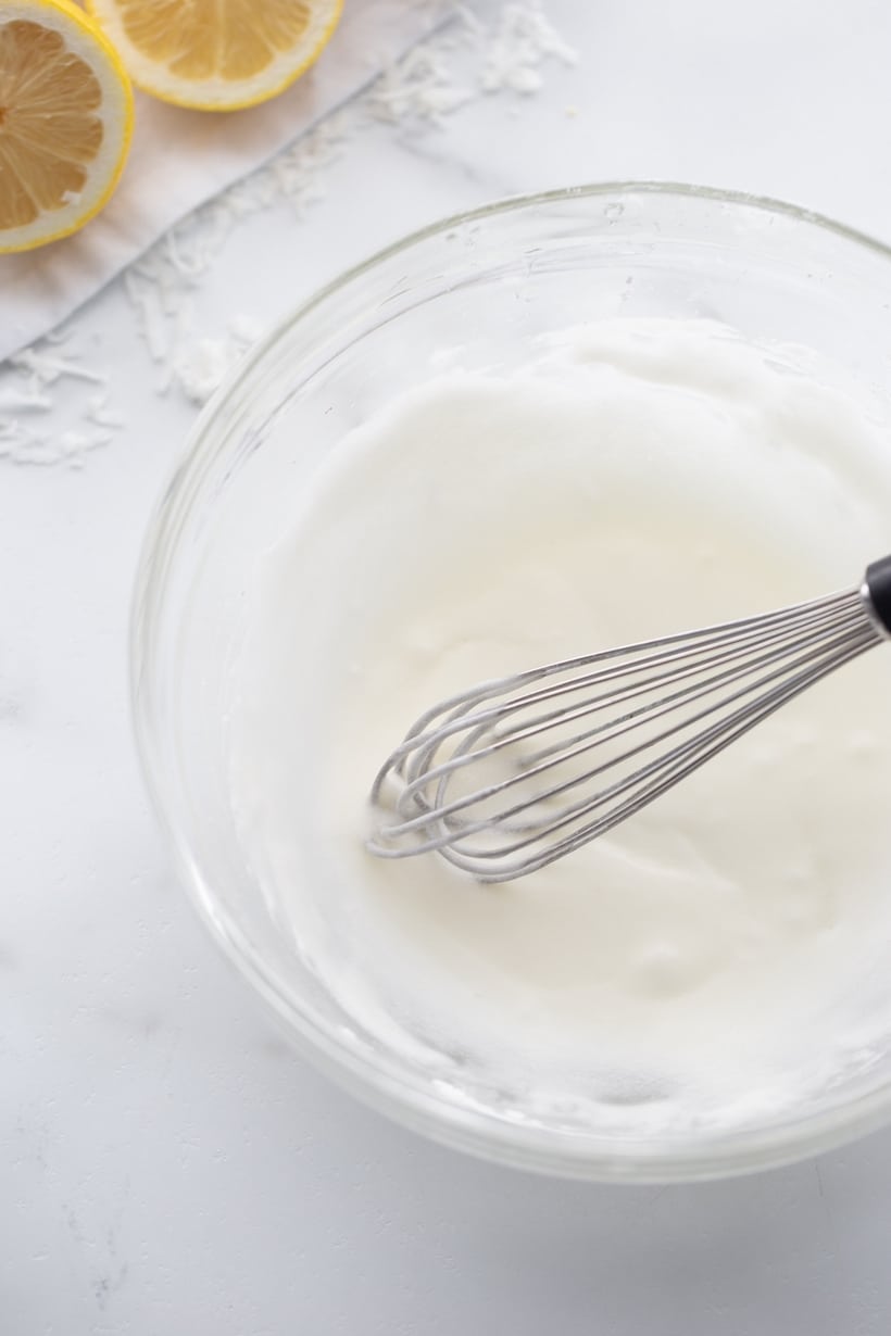 Whisking glaze in a clear bowl, ready to be drizzled on the baked loaf.