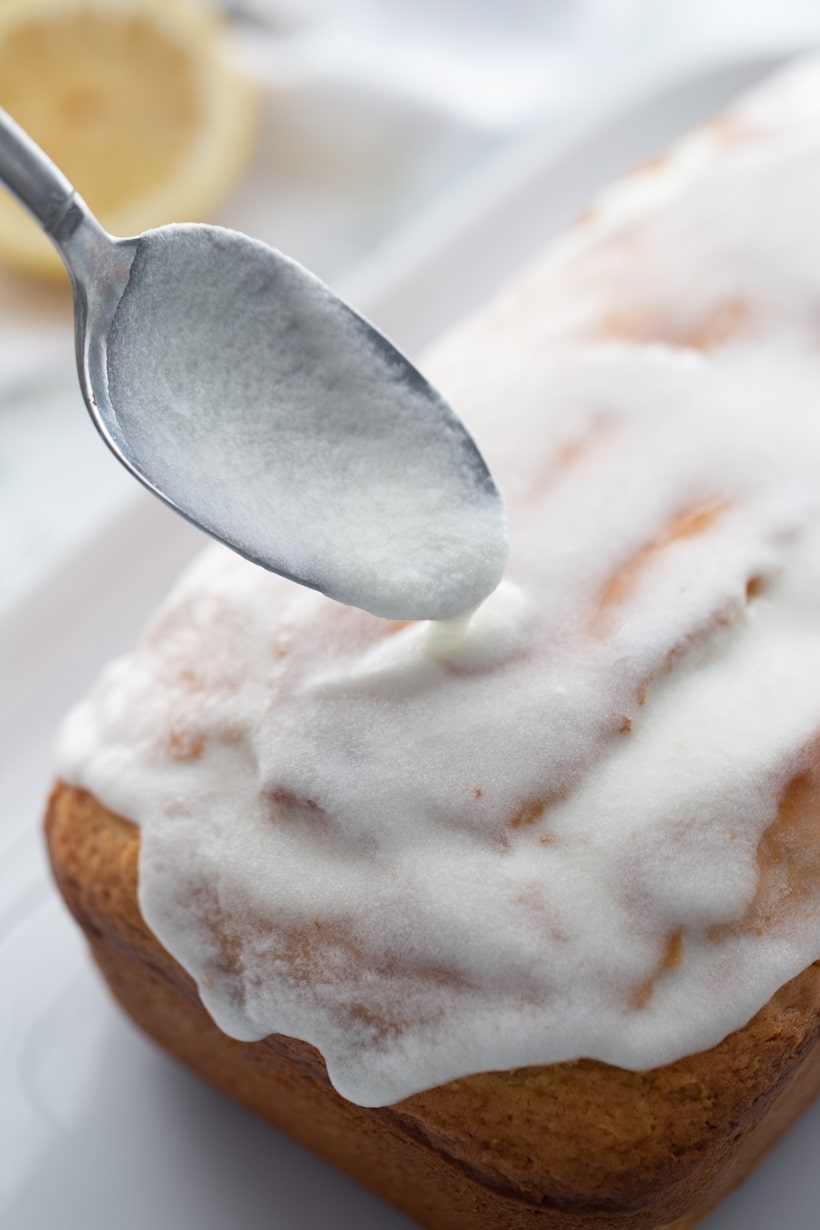 Spoon dripping glaze over the freshly baked loaf, adding a sweet finish.