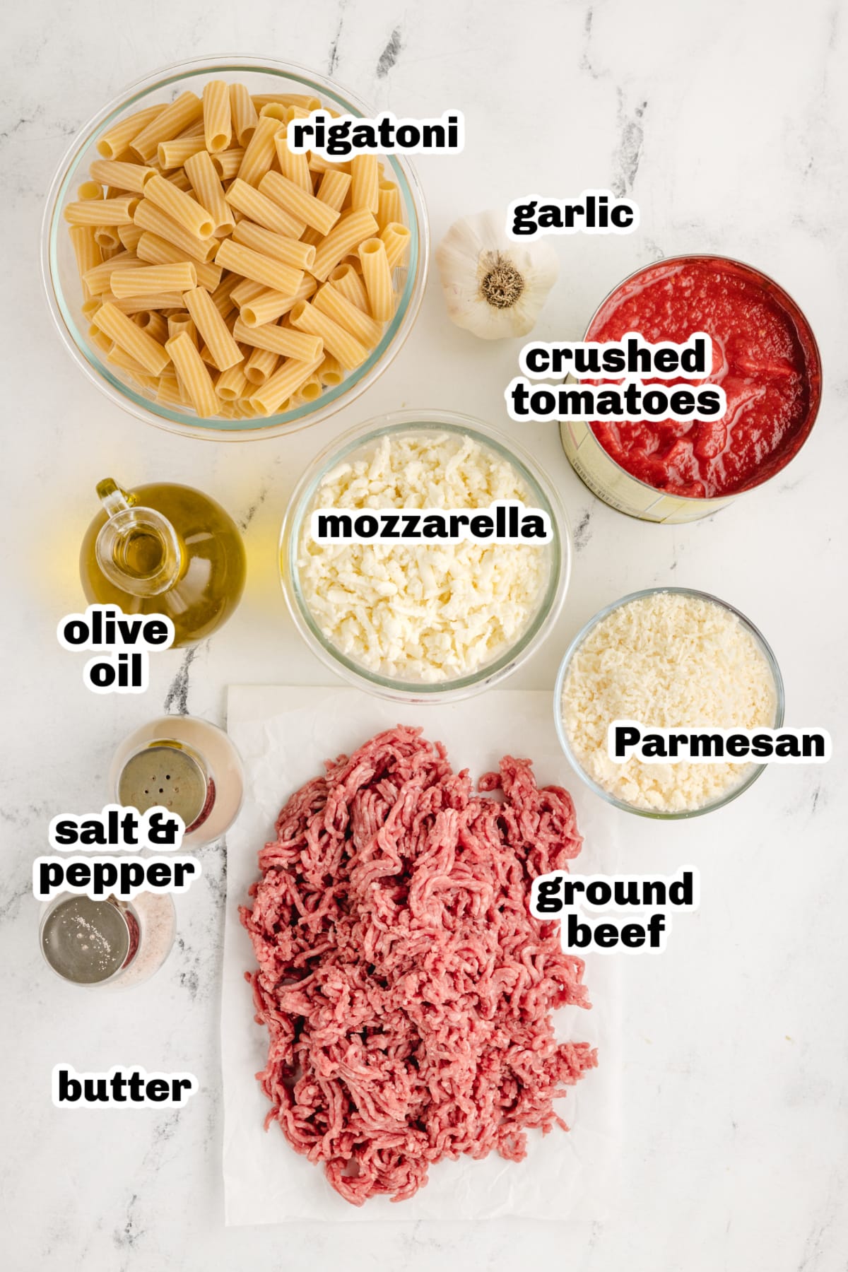 Pasta Pie ingredients A flat lay of the ingredients, including rigatoni, crushed tomatoes, Parmesan, mozzarella, ground beef, garlic, and seasonings.