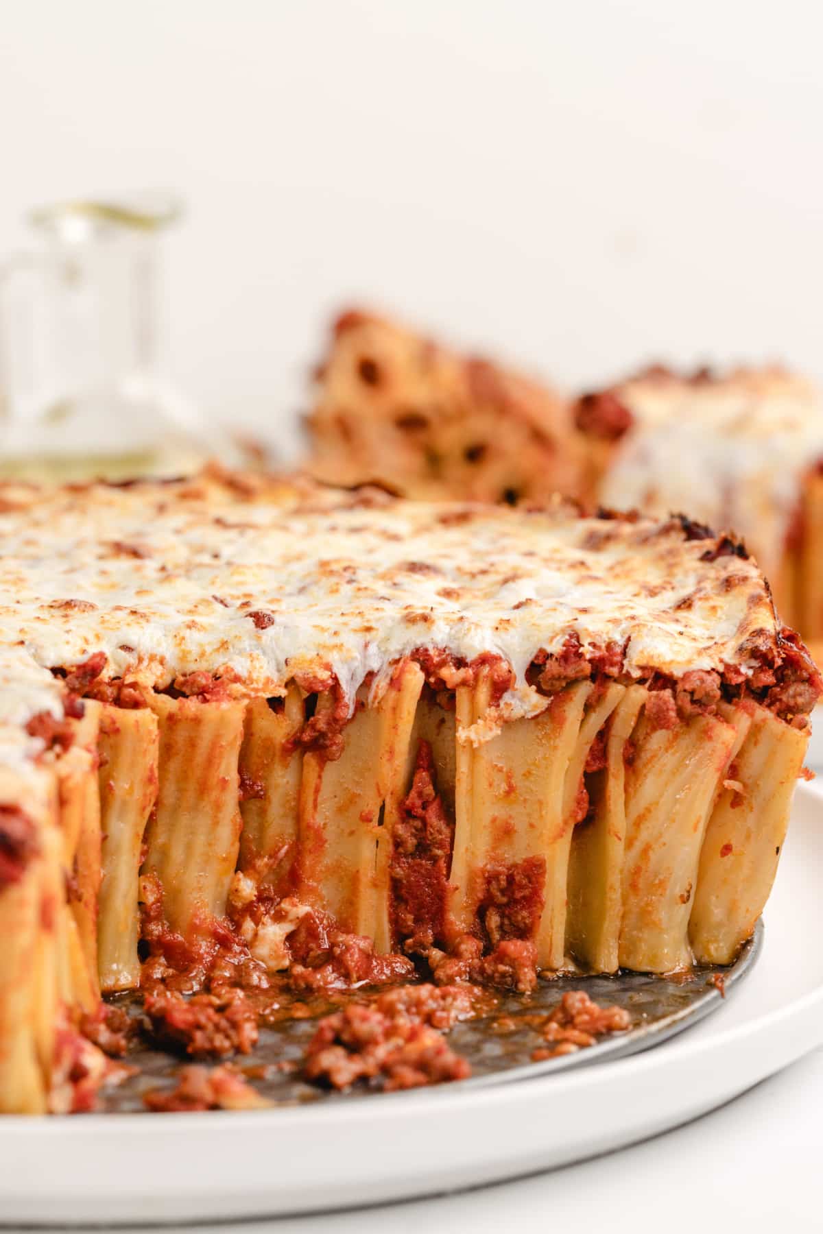 Pasta Pie with a piece missing A shot of the pasta pie with a slice removed, revealing the layers of rigatoni filled with meat sauce and topped with bubbly cheese.