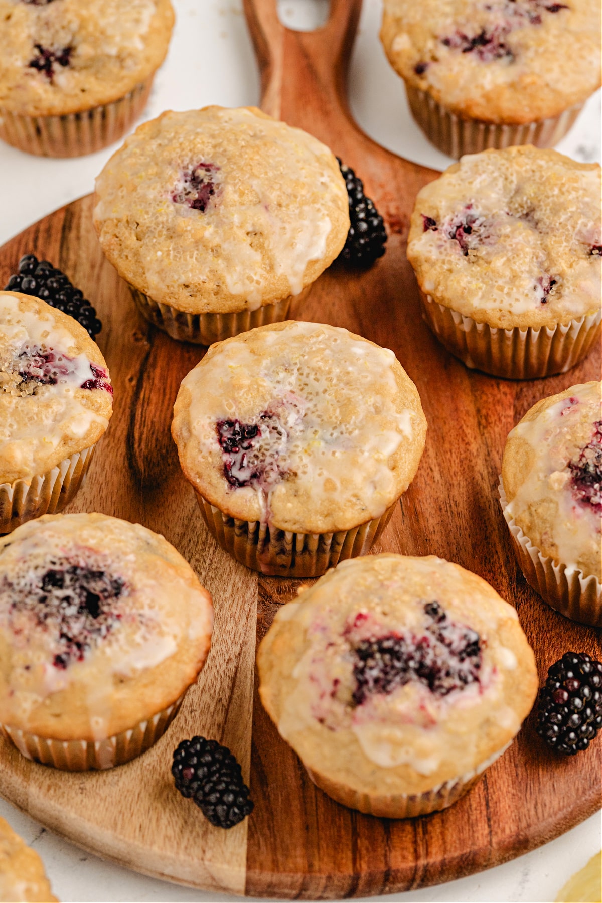 oat muffins with blackberries and lemon glaze arranged on a wooden board