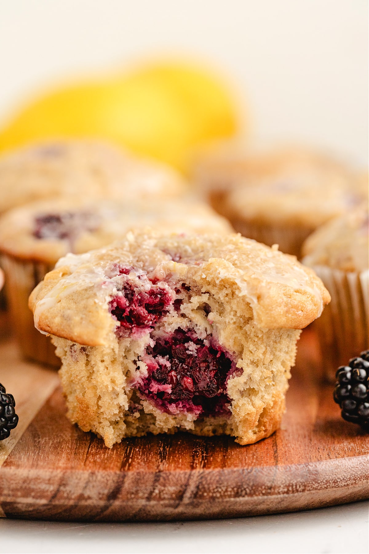 close-up of soft oat muffin with whole blackberries baked inside and light glaze on top