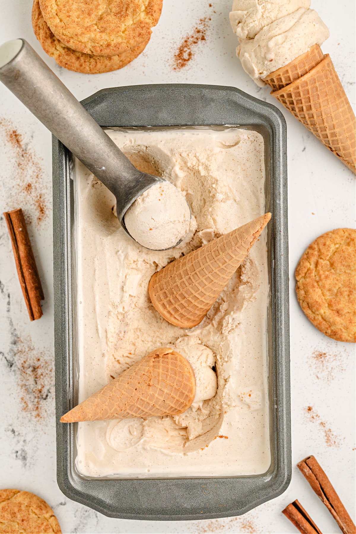 Loaf pan filled with homemade snickerdoodle ice cream and sugar cones.