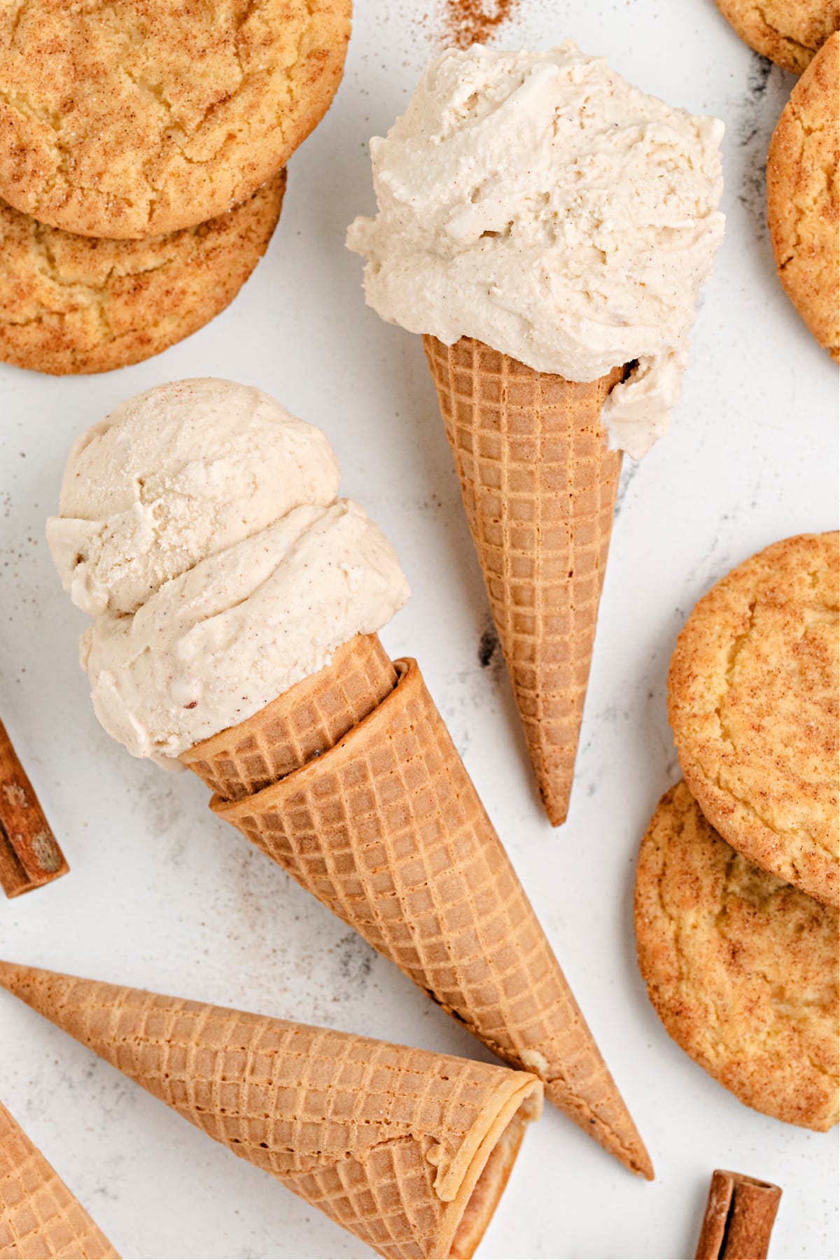 Two ice cream cones surrounded by snickerdoodle cookies.