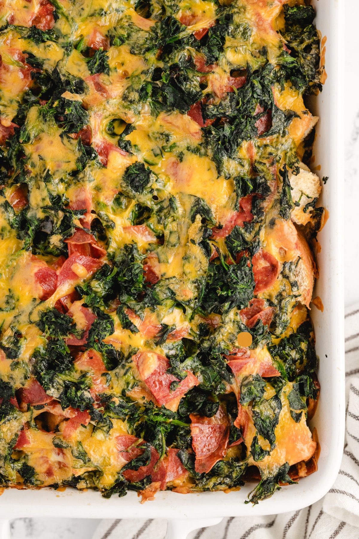Baked Cheesy Pepperoni Strata Closeup overhead shot of the corner of the baked strata showing crispy cheese and layered texture.