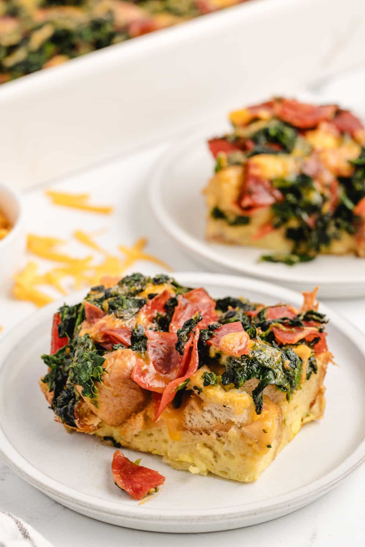 plated Cheesy Pepperoni Strata Two plates each with a slice of cheesy pepperoni strata, ready to serve.