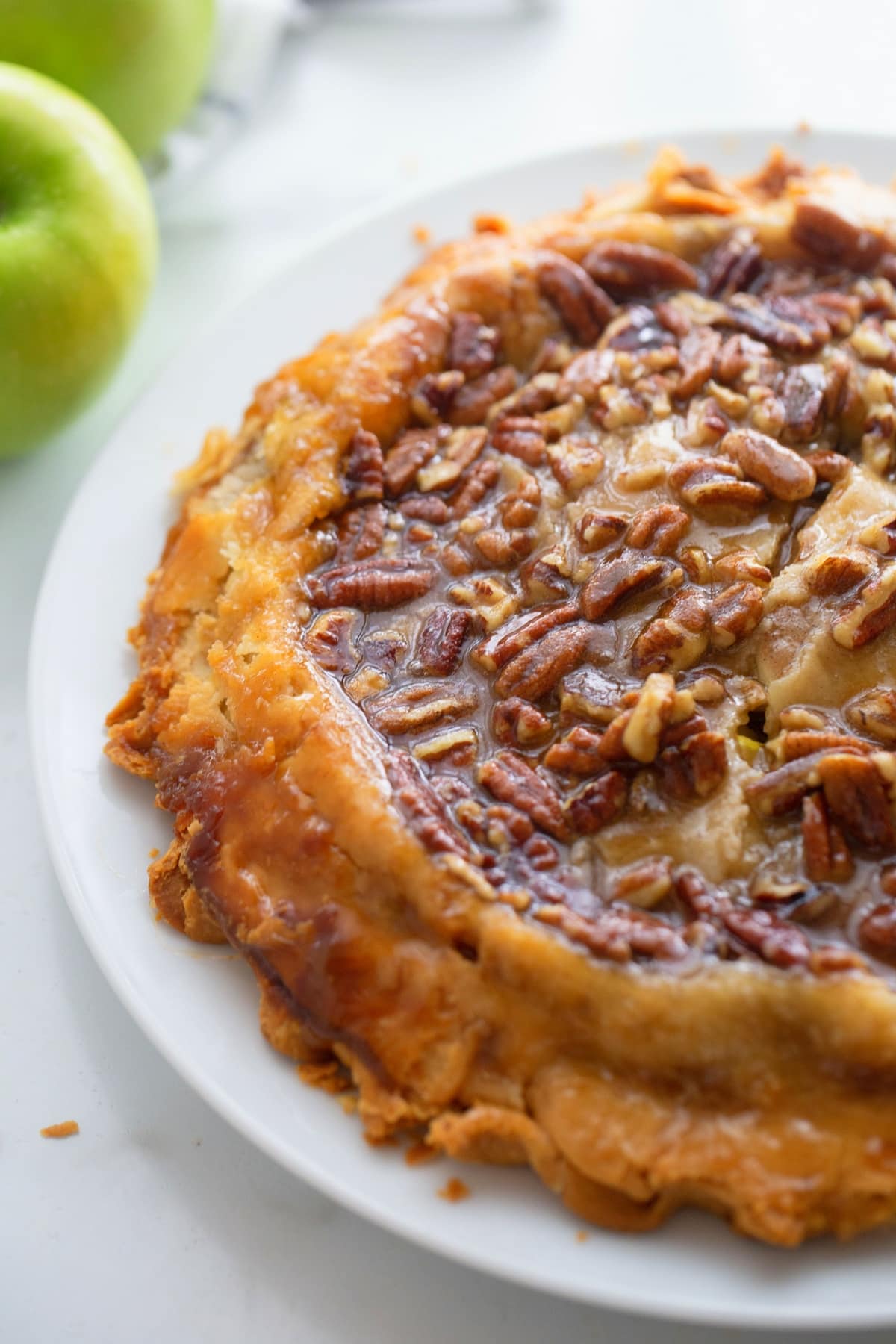 This upside down apple pie is easy to make and turns out beautifully every time—no crust-making skills needed. It has rave reviews and is a favorite for Thanksgiving or any holiday table. upside down apple pie with brown sugar, pecand and refrigerated dough from Noble Pig.