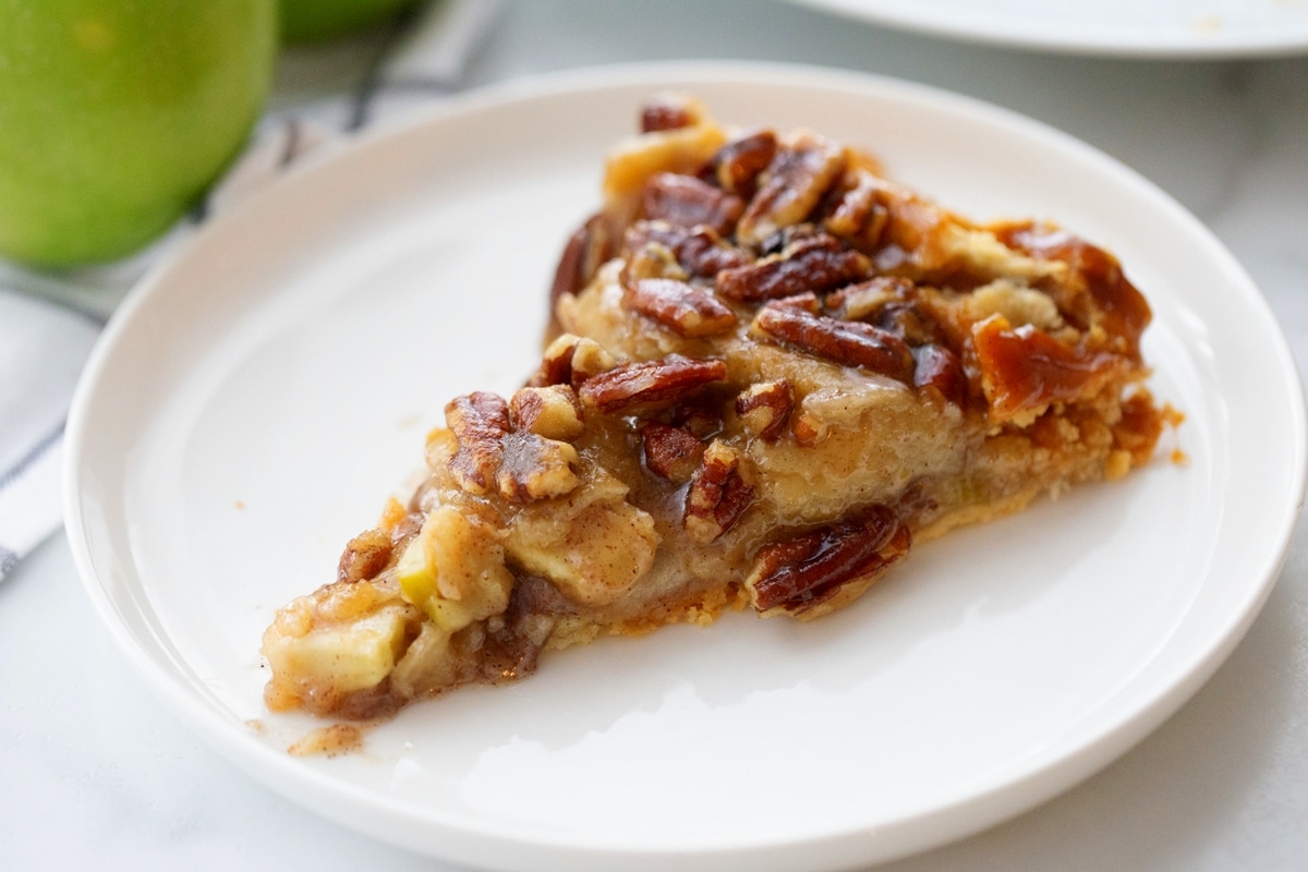This upside down apple pie is easy to make and turns out beautifully every time—no crust-making skills needed. It has rave reviews and is a favorite for Thanksgiving or any holiday table. slice of apple pie