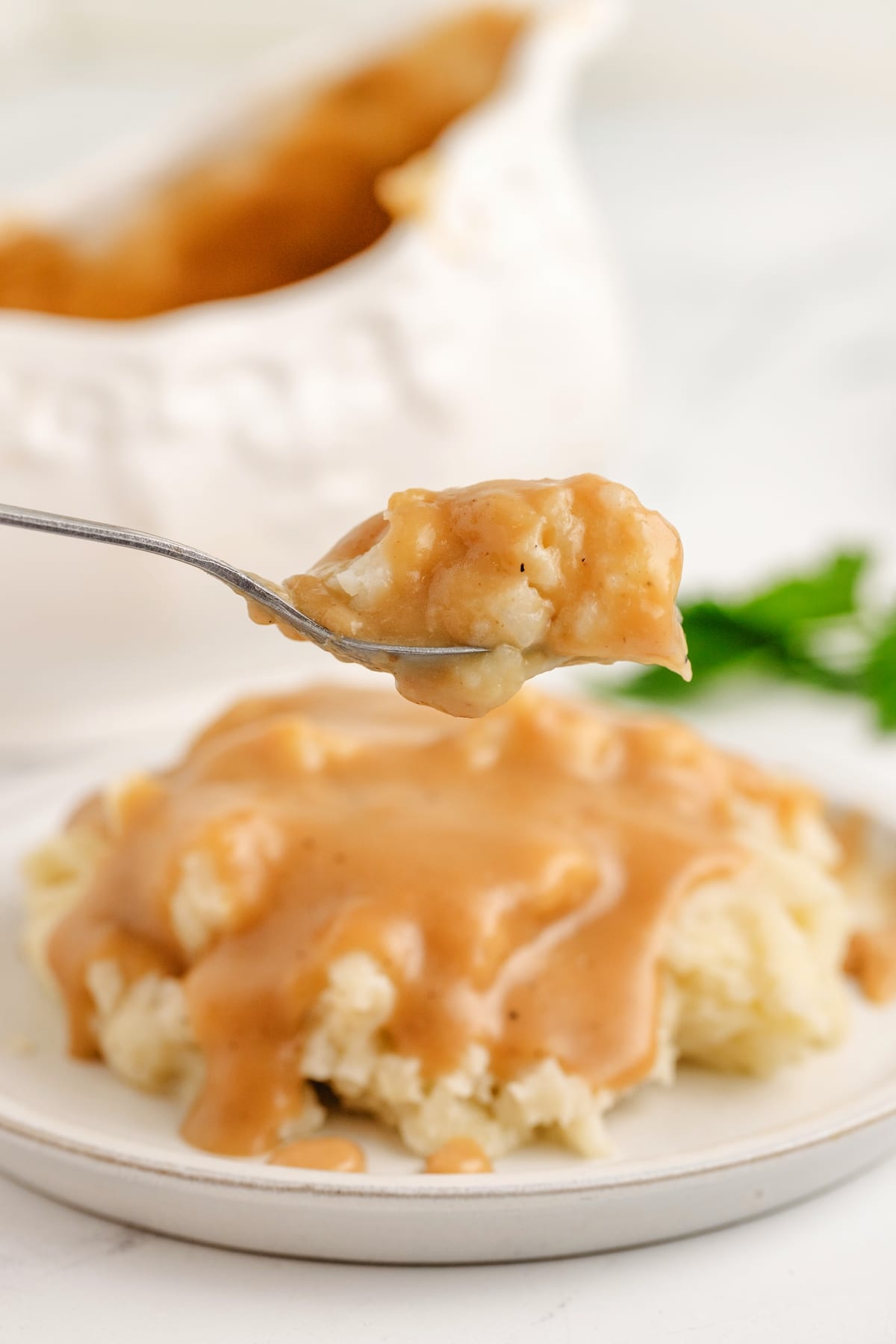 Best Make Ahead Turkey Gravy Recipe Spoonful Spoonful of creamy make ahead turkey gravy recipe being drizzled over mashed potatoes. Smooth, rich, and perfect for Thanksgiving dinner or holiday prep.