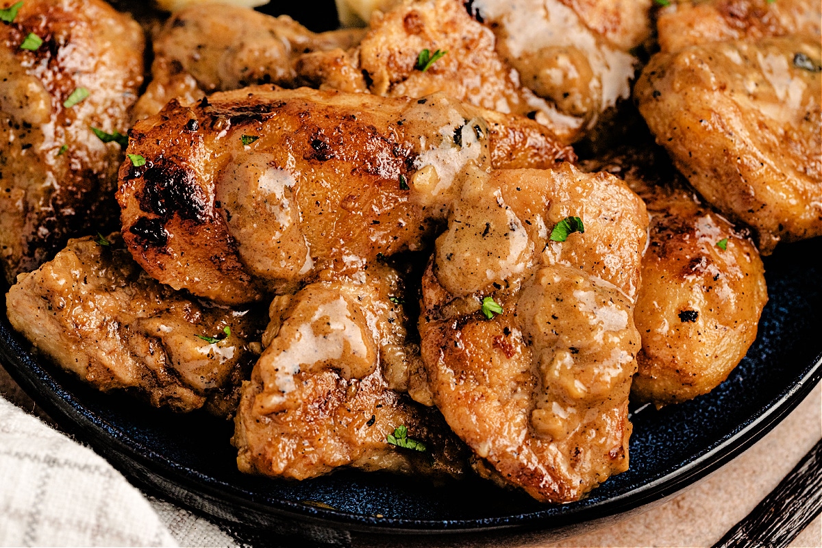Close-up of pork with pears coated in creamy cider sauce, showing golden edges and tender texture, by Noble Pig.