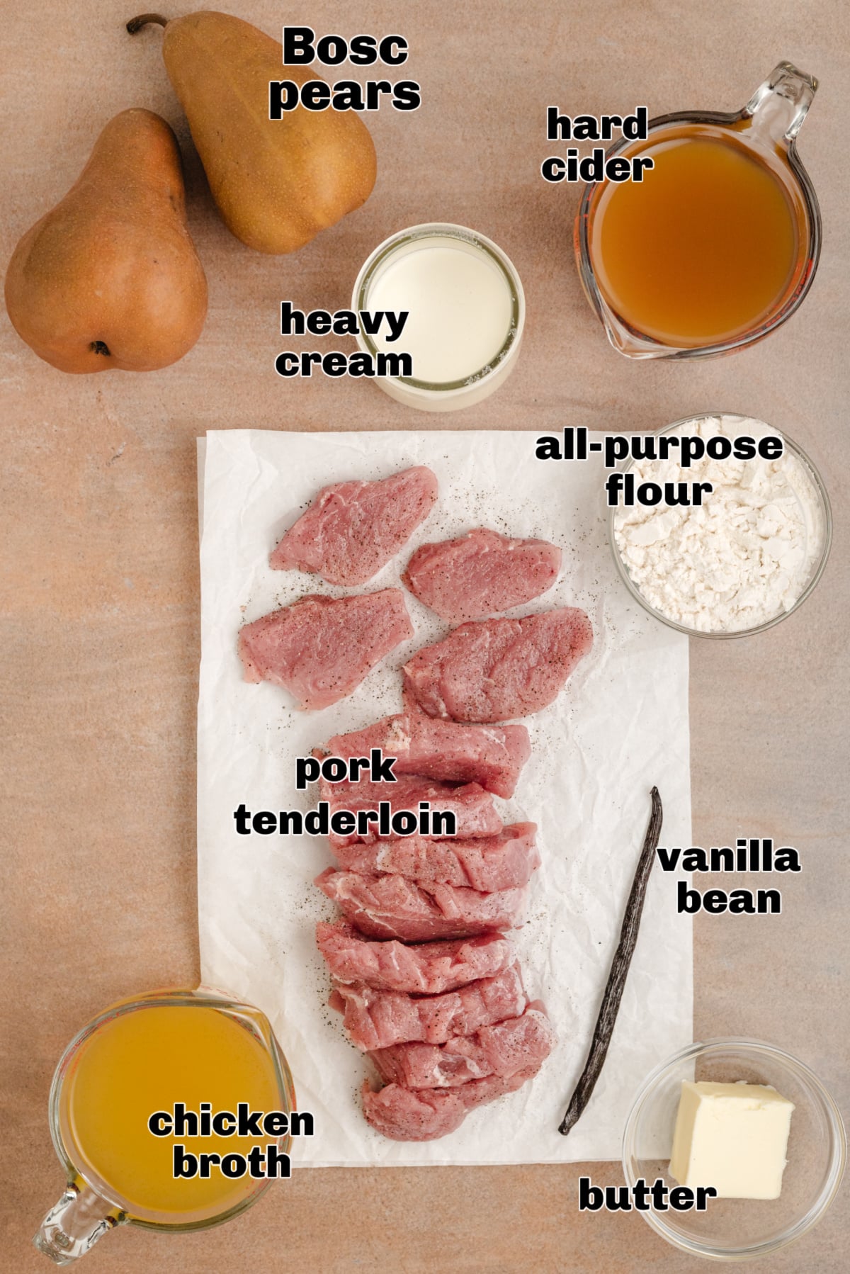 Ingredients for cider cream sauce with pork tenderloin, Bosc pears, hard cider, and vanilla bean arranged on parchment.
