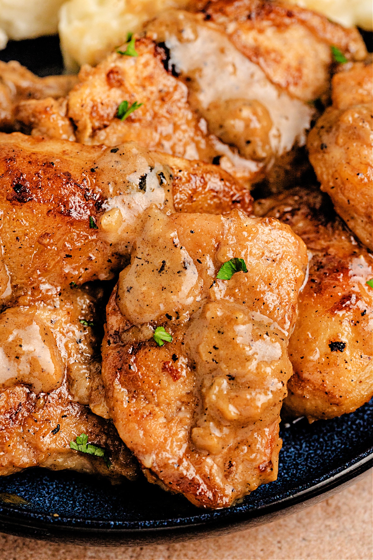 Close-up of Vanilla Cider Pork with caramelized Pears covered in creamy cider-vanilla sauce and garnished with fresh herbs.