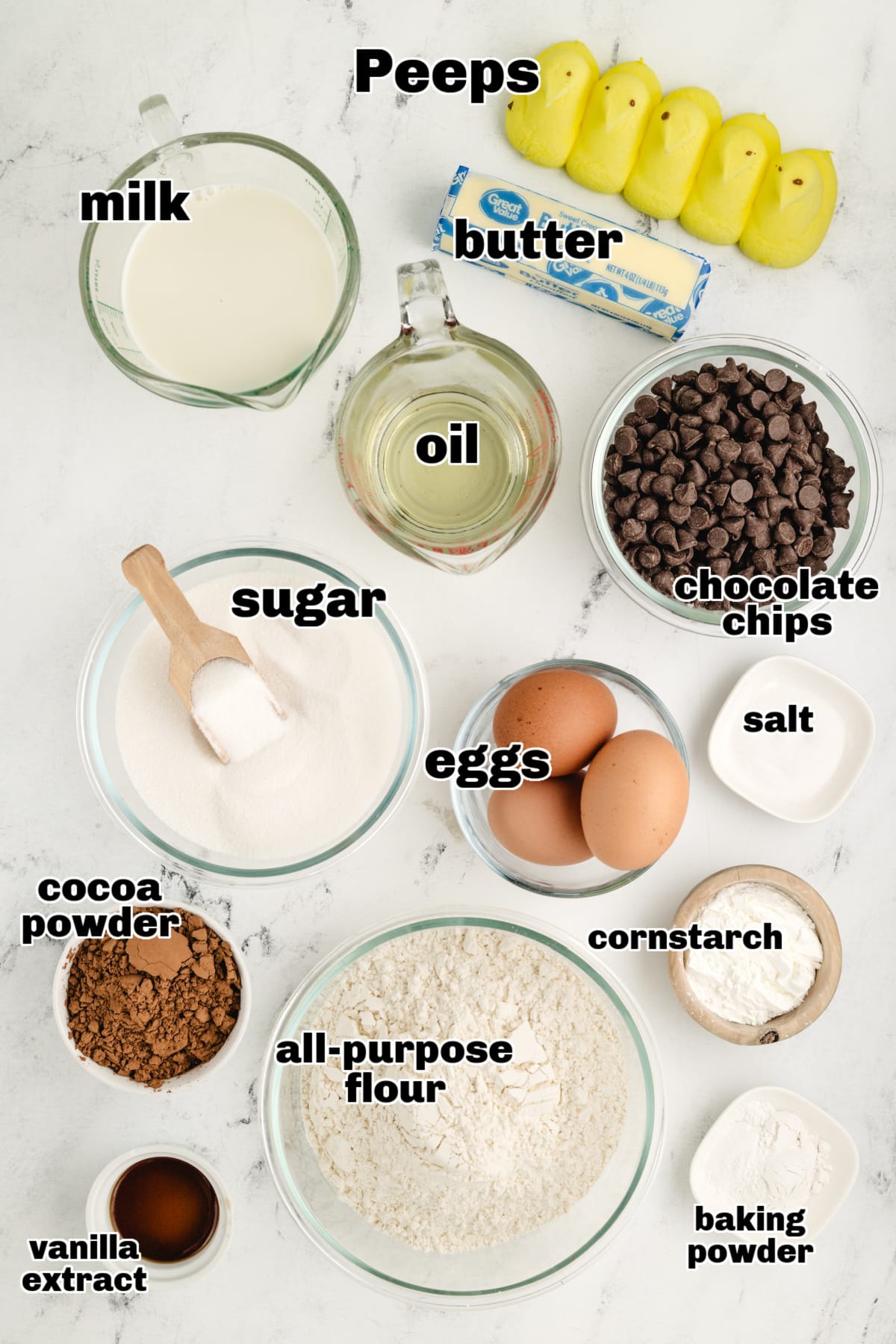 Overhead view of the ingredients for Peeps Sunflower Layer Cake, including flour, sugar, eggs, butter, cocoa, Peeps, and chocolate chips.