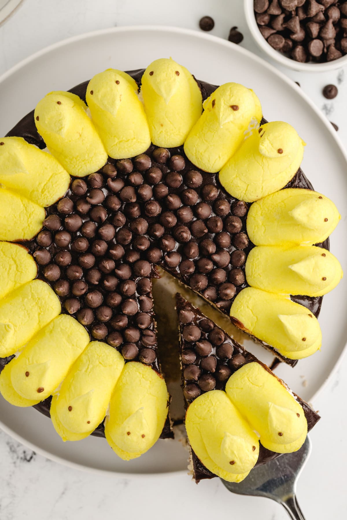 Overhead shot of a cake slice being lifted from the whole Peeps Sunflower Layer Cake, showing the sunflower design and cake layers.