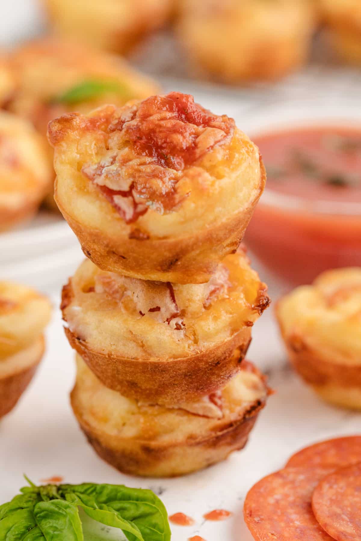 Another angle of three stacked pizza puffs, highlighting the bits of pepperoni and melted mozzarella in each bite. 