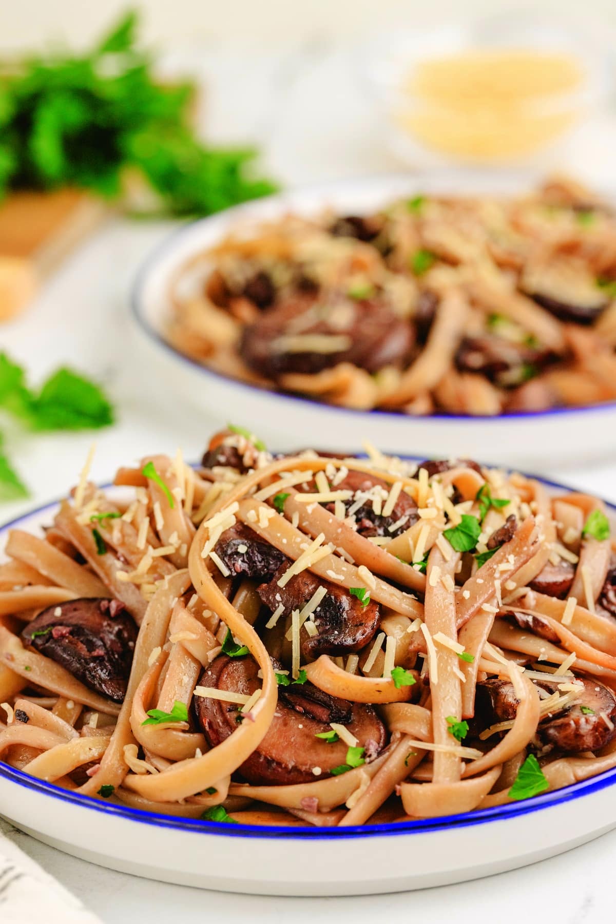 Creamy mushroom fettuccine pasta topped with Parmesan and parsley served on a plate