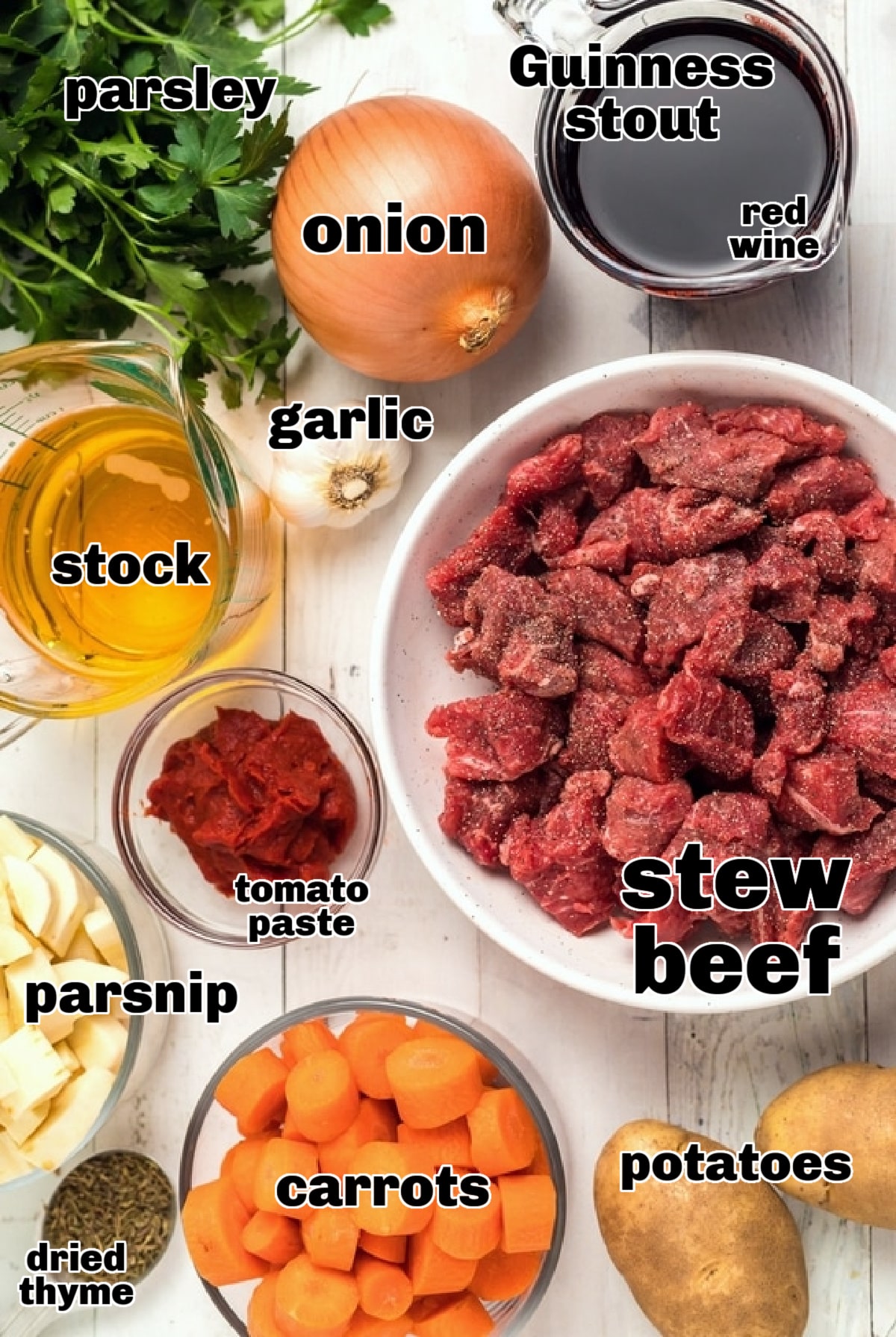 Beef Irish Stew ingredients Overhead shot of all the ingredients for Beef Irish Stew, including beef, potatoes, carrots, parsnips, Guinness, and seasonings, arranged on a countertop.