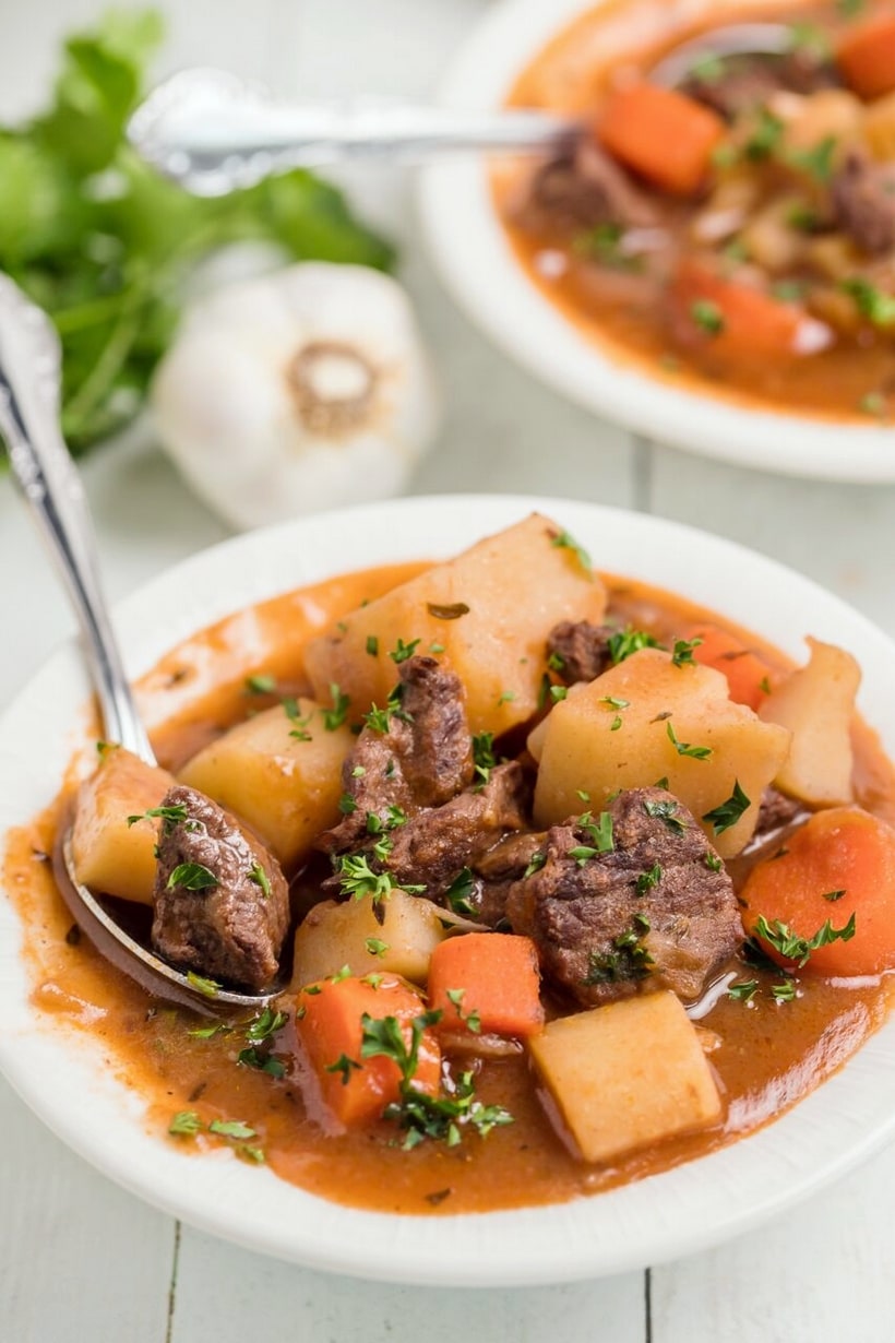 Beef Irish Stew in a bowl A bowl of Beef Irish Stew with chunks of tender beef, potatoes, and carrots in a thick, rich broth, garnished with fresh parsley.