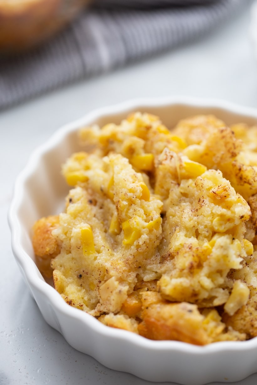 Side view of a ramekin filled with corn pudding, highlighting its creamy and spoonable texture.