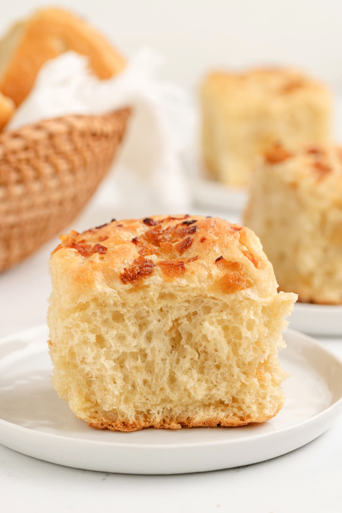 No-Knead Onion Rolls on a plate A soft, golden-brown onion roll with caramelized onions on top, showing its fluffy texture.