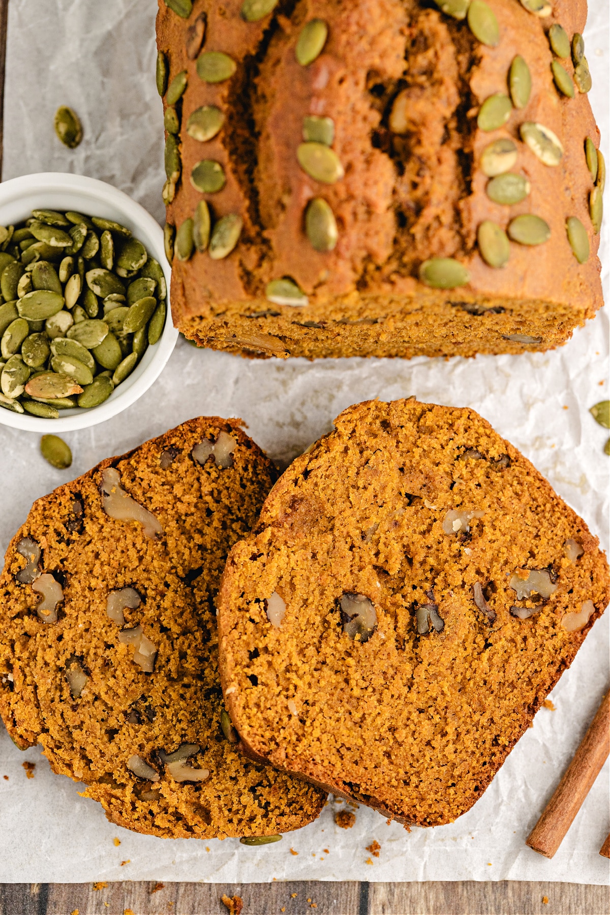 Pumpkin Walnut Bread Pumpkin walnut bread slices on parchment with pepitas.