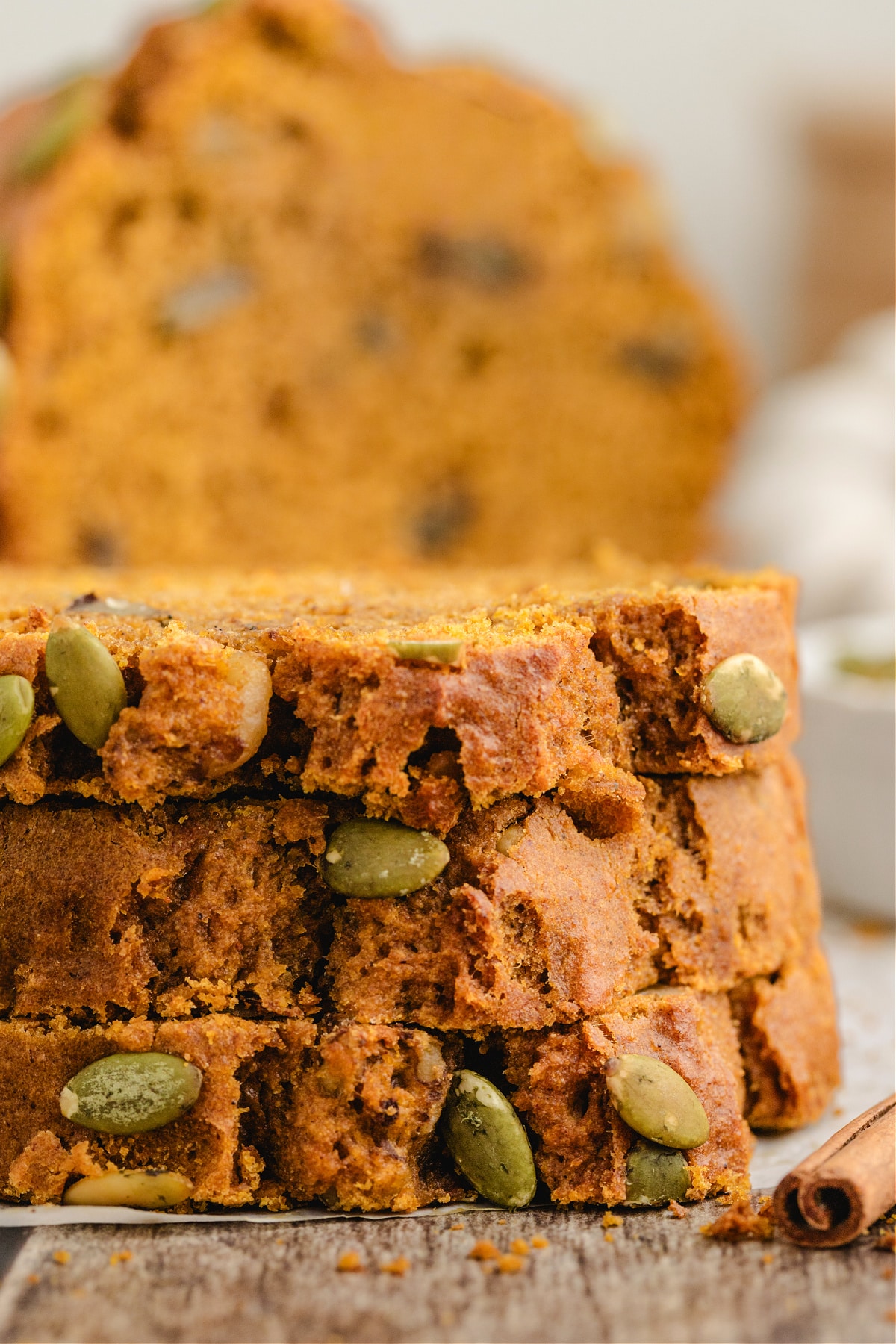 Pumpkin Loaf Slices Soft pumpkin loaf slices stacked with pepitas on the crust.