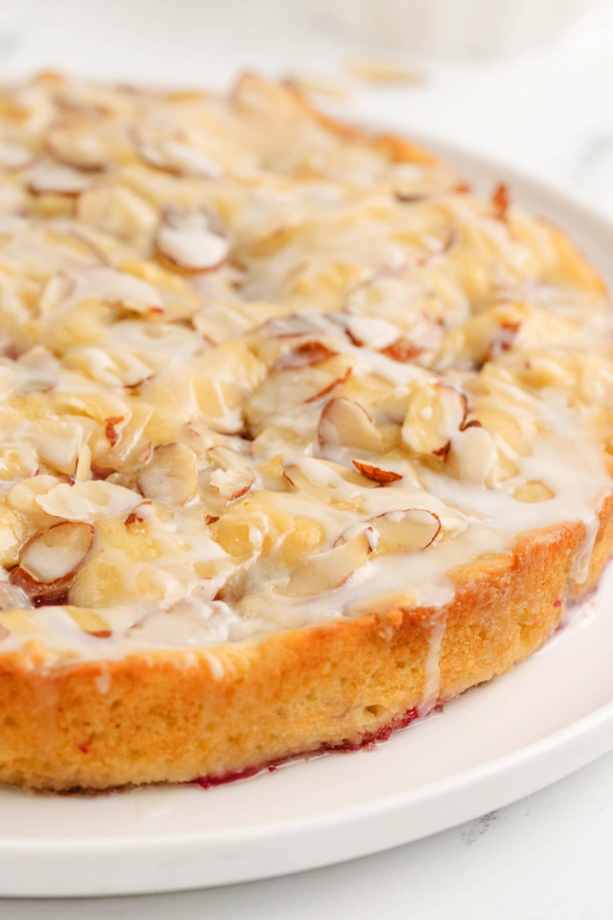 Full raspberry almond coffee cake intact in the pan, showing the golden-brown top with sliced almonds and pockets of raspberries.